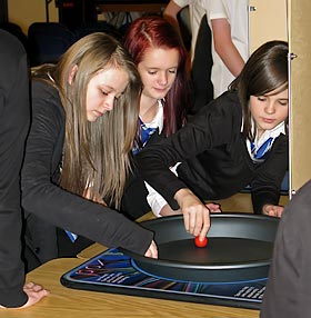 Three girls investigating Tippy Tops during a school visit