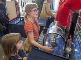 A girl investigates how electricity is generated with a smaller girl looking on