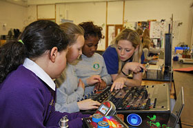 A University of Edinburgh student demonstrates the Periodic Table exhibit to a group of three girls