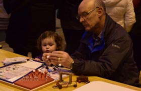 A gentleman attempts to build a molecule model whilst a little girl watches