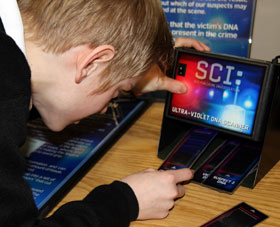 A boy investigates the DNA samples within the Forensics exhibit