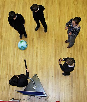 An overhead view of a group of boys investigating the Coanda Effect with a teacher looking on